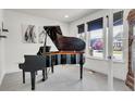 Bright sitting room with black grand piano, neutral walls, and ample natural light from a nearby window at 3421 E 143Rd Dr, Thornton, CO 80602