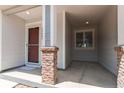 Inviting covered front porch with brick columns and a sheltered entry at 19043 E 58Th Ave, Denver, CO 80249