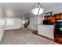 Open-concept living area featuring neutral carpet, staircase, and kitchen access at 19043 E 58Th Ave, Denver, CO 80249