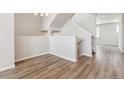 An open concept living room shows a stairwell and grey wood flooring at 457 Interlocken Blvd # 106, Broomfield, CO 80021
