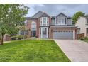 Attractive two-story home with brick accents, a manicured lawn, and an attached two-car garage at 9458 S Hackberry Ln, Highlands Ranch, CO 80129