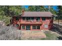 Rear exterior featuring a spacious second-story deck, walk-out basement, and landscaped area at 767 Tenderfoot Dr, Larkspur, CO 80118