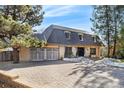 Inviting two-story home with a brick driveway, attached garage and unique roof amidst mature trees at 6382 S Zenobia Ct, Littleton, CO 80123