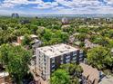 Aerial view of a brick apartment building surrounded by trees and featuring a cityscape in the background at 1050 N Lafayette St # 408, Denver, CO 80218