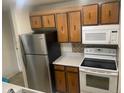 Functional kitchen equipped with stainless steel refrigerator, white range and microwave, plus wood cabinets at 707 W 96Th Ave # 9, Thornton, CO 80260