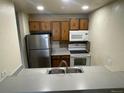 Cozy kitchen features stainless steel refrigerator, white appliances, and oak-style cabinetry at 707 W 96Th Ave # 9, Thornton, CO 80260