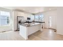 Bright kitchen boasts stainless appliances, island, and white cabinets with dark countertops at 712 N Bently St, Watkins, CO 80137