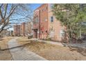 Beautiful condo building with landscaped grounds, a walkway and colorful red brick and neutral stucco exterior at 14321 E Tennessee Ave # 1-307, Aurora, CO 80012