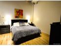 Well-lit bedroom with hardwood floors, a comfortable bed, and ample storage in side tables and cabinet at 1450 Wynkoop St # 3F, Denver, CO 80202