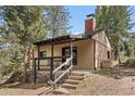 Quaint cabin featuring a covered porch with seating and natural rock outcroppings at 32173 Soda Creek Dr, Evergreen, CO 80439