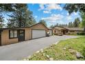 Exterior of home shows large garage, mature trees, landscaping, and a long driveway at 32173 Soda Creek Dr, Evergreen, CO 80439