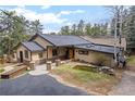 Charming exterior view showcasing the lush landscaping and unique architecture of this inviting home at 32173 Soda Creek Dr, Evergreen, CO 80439