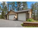 Three car garage with an outdoor pizza oven on a spacious driveway surrounded by mature trees at 32173 Soda Creek Dr, Evergreen, CO 80439