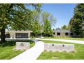 Elegant ranch-style home featuring a winding concrete driveway, lush lawn, and a modern garage with glass panels at 3355 E Eastman Ave, Denver, CO 80210