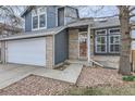 Detailed view of a home's exterior with blue siding, brick accents, a two-car garage, and a walkway at 9902 Independence St, Broomfield, CO 80021