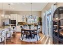 Well-lit dining area with a table, a modern light fixture, and a view into the kitchen through a sliding glass door at 3309 Thornwood Ct, Castle Rock, CO 80108