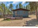Attractive blue cabin with deck and steps, surrounded by trees at 28 Deer Rd, Evergreen, CO 80439
