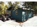 Side view of a charming blue cabin with a deck and snowy landscape at 28 Deer Rd, Evergreen, CO 80439