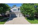 Charming two-story home featuring an attached three-car garage, attractive landscaping, and mature trees enhancing the property's appeal at 9845 Keenan St, Highlands Ranch, CO 80130