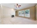 Bright living room with a cozy fireplace, built-in shelves, and three large windows overlooking the backyard at 9845 Keenan St, Highlands Ranch, CO 80130