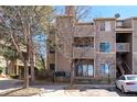 Multi-story condo building featuring stone accents, balconies, and mature trees on a sunny day at 7414 S Alkire St # 101, Littleton, CO 80127