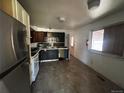 Kitchen with stainless steel refrigerator, dark cabinetry, tile floor, and door to backyard at 1021 Downing Way, Denver, CO 80229