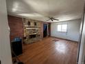Living room featuring stone fireplace, ceiling fan, wood flooring, and natural light at 1021 Downing Way, Denver, CO 80229