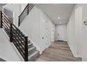 Bright entryway featuring wood floors, staircase with dark wood rails, and white trim at 6220 Waterman Way, Frederick, CO 80516