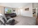 Bright living room with vaulted ceilings, large window, neutral carpet, and cozy furnishings at 1030 S Fulton Ave, Fort Lupton, CO 80621