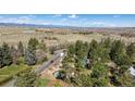 High-angle aerial view captures the home's location amidst trees, with a field and distant mountains at 7904 Hill Crest Dr, Louviers, CO 80131