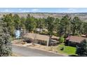 Scenic aerial view of a home nestled among lush trees with a distant view of rolling hills at 7904 Hill Crest Dr, Louviers, CO 80131