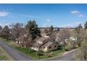 Aerial view of charming yellow home with inviting front porch, surrounded by mature trees and a green lawn at 7835 Valley View St, Louviers, CO 80131