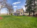 Expansive backyard featuring lush green lawn and a charming yellow home with screened-in porch at 7835 Valley View St, Louviers, CO 80131