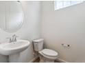 Clean powder room with pedestal sink and stylish round mirror at 19080 E 96Th Pl, Commerce City, CO 80022
