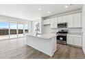 Modern kitchen with white cabinetry, stainless steel appliances, and large island at 19080 E 96Th Pl, Commerce City, CO 80022