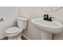 Clean and modern bathroom with pedestal sink and white toilet at 3242 Boral Owl Dr, Brighton, CO 80601