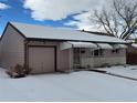 Ranch style home with attached garage and snow-covered front yard at 1851 S Perry Way, Denver, CO 80219