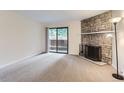 Bright living room with a stone fireplace, sliding glass door and neutral carpet at 3315 S Ammons St # 103, Lakewood, CO 80227