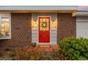 Close-up of the red front door with glass insert and a wreath, flanked by sconces and house numbers at 6984 E Montana Pl, Denver, CO 80224