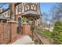Inviting brick entrance with iron gate leads to a charming Tudor-style townhome with manicured landscaping at 76 S Garfield St, Denver, CO 80209
