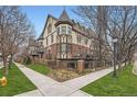 Elegant townhome showcases Tudor architecture, private balconies, iron railings, and lush landscaping on a sunny corner lot at 76 S Garfield St, Denver, CO 80209