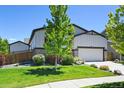 Beautifully landscaped home featuring a well-manicured lawn and a two-car garage at 6049 Sandstone Cir, Erie, CO 80516