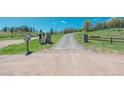Long private driveway leading to the home, passing a gated entry and a mailbox on lush green grass at 1549 Hillside Cir, Sedalia, CO 80135