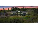 Expansive home with large windows, stone accents, a deck, mature trees and metal outbuilding at 1549 Hillside Cir, Sedalia, CO 80135