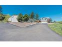 Home and adjacent metal outbuilding with a long driveway and plenty of parking space on gravel at 1549 Hillside Cir, Sedalia, CO 80135