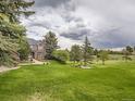 Spacious front yard featuring mature trees, lush lawn, and a classic brick home with elegant architectural details at 18963 E Long Ave, Centennial, CO 80016