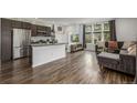 Open concept layout with an island kitchen flowing to a living room with large windows and hard floors at 1754 W 66Th Ave, Denver, CO 80221