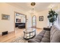 Cozy living room showcases hardwood floors, a plush gray sofa, and a glass coffee table with open archway at 826 Maxwell Ave, Boulder, CO 80304