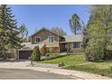 Charming two-story home featuring stone accents, a well-manicured lawn, and mature trees at 1973 S Pitkin St, Aurora, CO 80013