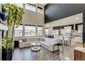 Bright, open-concept living room boasts large windows, high ceilings, and stylish decor with view into the kitchen at 16978 W 87Th Ave, Arvada, CO 80007
